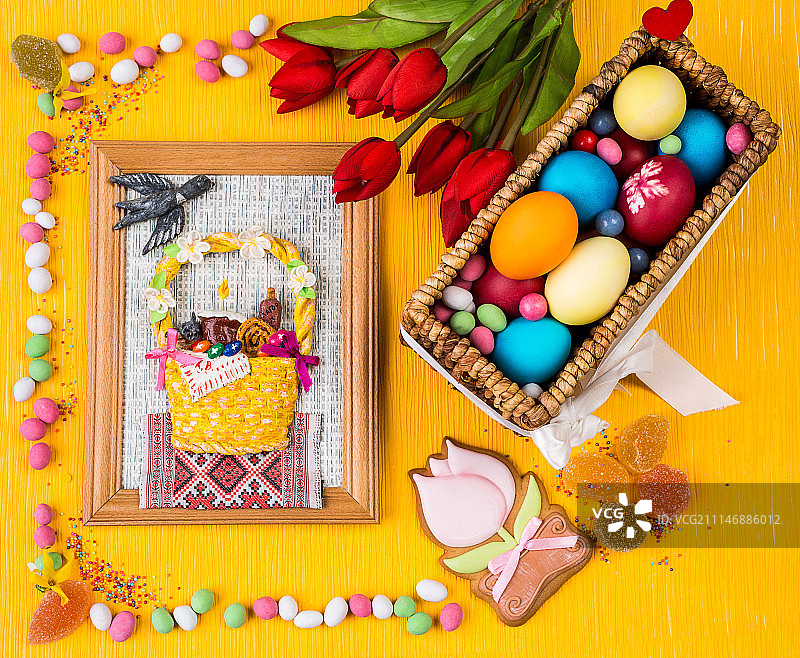 复活节彩色背景。篮子里有彩绘的鸡蛋，桔子上有糖果和鲜花……图片素材