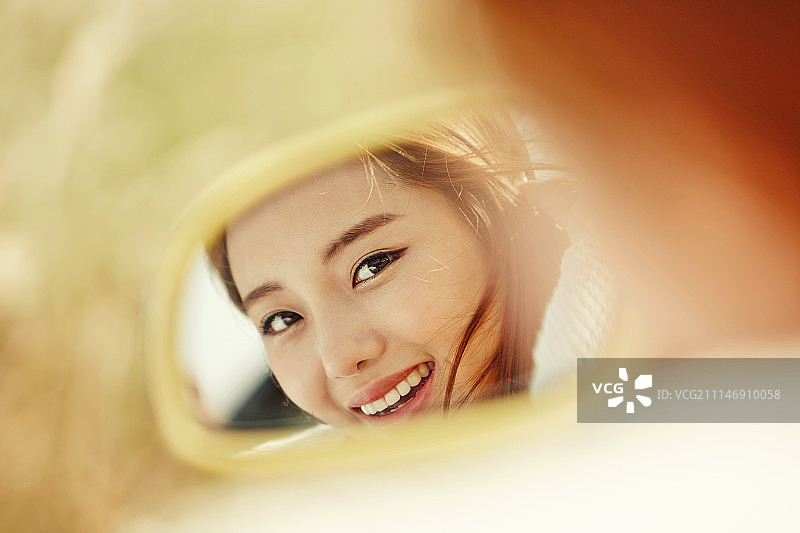 摄影的年轻女子反映在汽车的镜子图片素材
