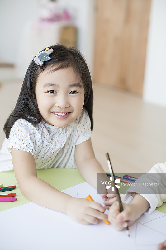 小女孩用彩色铅笔在白纸上画画图片素材