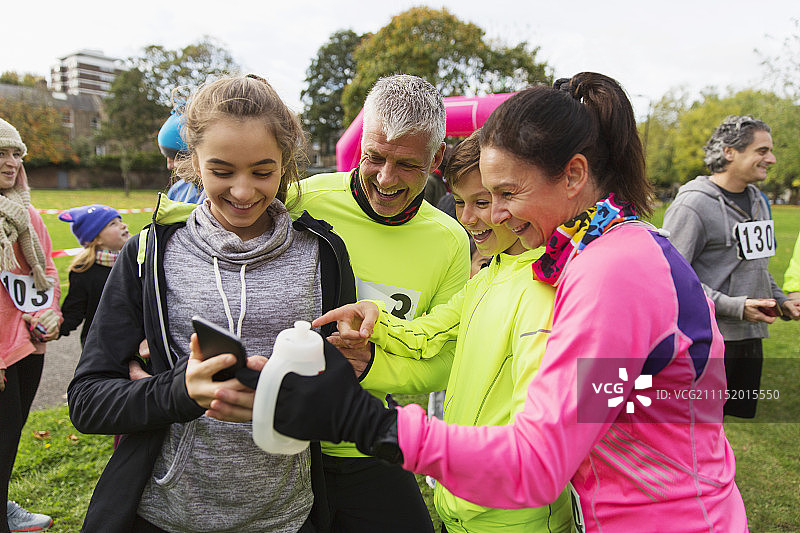 带着智能手机的家庭跑步者在公园里参加慈善跑步图片素材