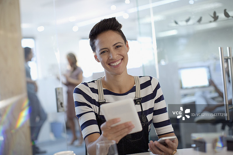 肖像微笑，自信，有创意的女商人使用数字平板电脑在办公室图片素材
