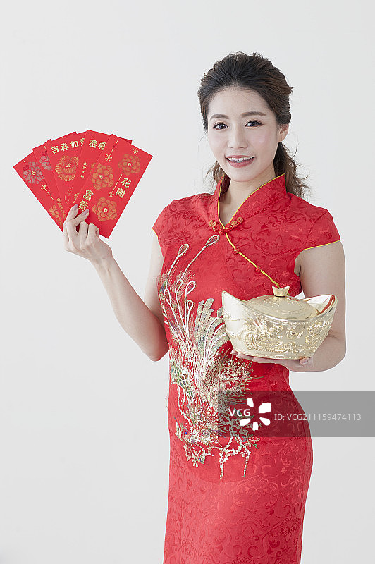 年轻女人穿旗袍拿着红包与金元宝图片素材
