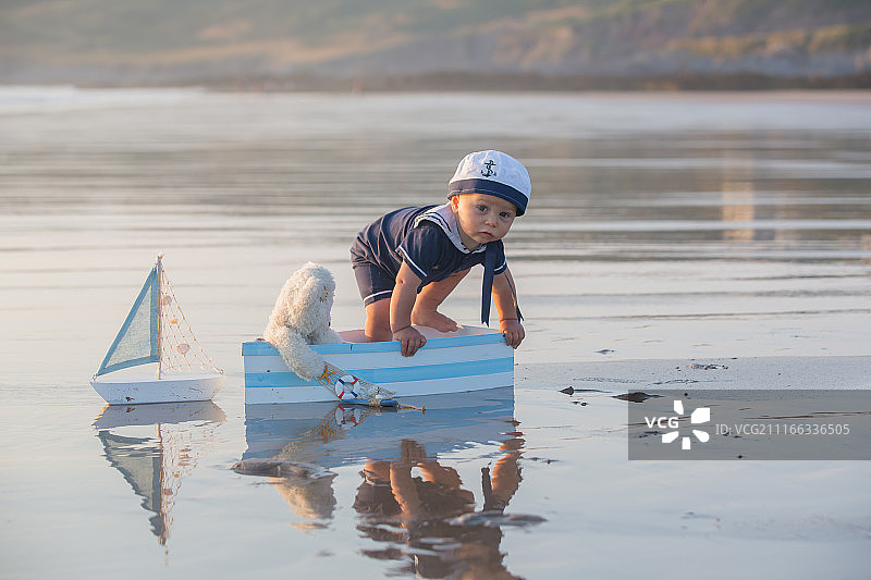 小男孩在夏天的海滩上当水手玩图片素材