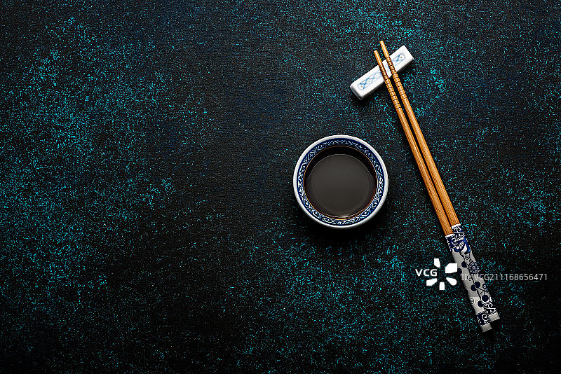 日本寿司筷子和酱油碗在蓝色的黑色石头背景图片素材
