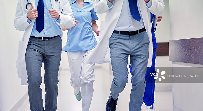 医疗保健，人和医学概念-近距离观察医生或医生在医院走廊上奔跑。医护人员或医生在医院跑步的特写图片素材