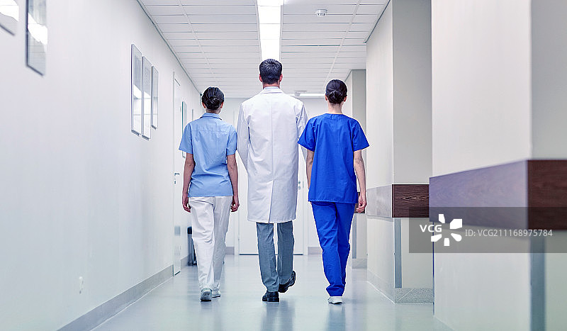 诊所、专业、人、保健和医学概念——沿着医院走廊行走的一群医生或医生。一群医生在医院里散步图片素材