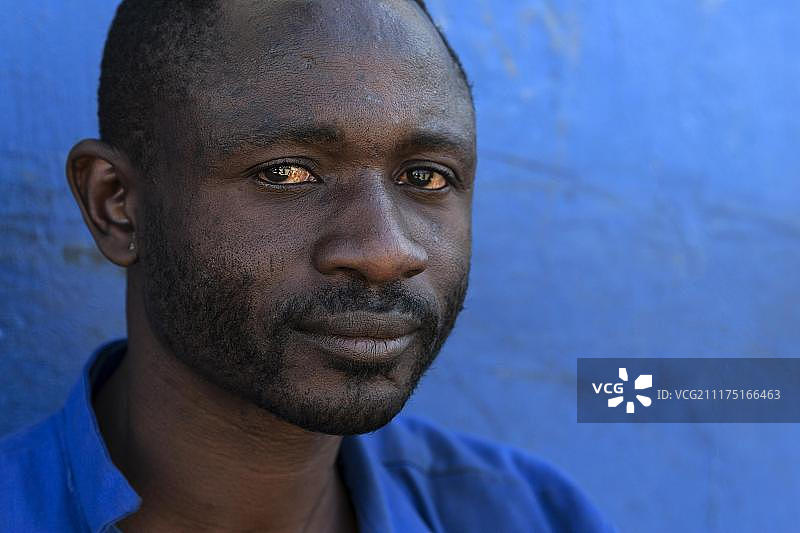 在非洲纳米比亚的斯瓦科普蒙德，一个当地人靠在蓝色的墙上图片素材