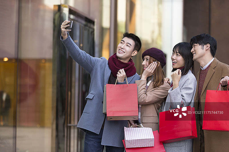 快乐的年轻人在购物中心用手机自拍图片素材