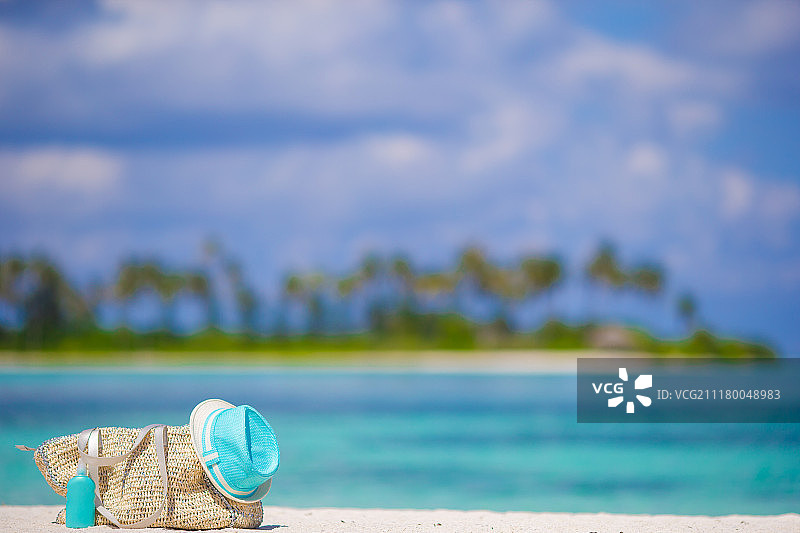 草袋，蓝帽子，太阳镜和防晒瓶在热带海滩图片素材