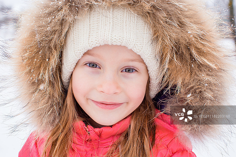 白雪明媚的冬日里可爱的小女孩的肖像图片素材