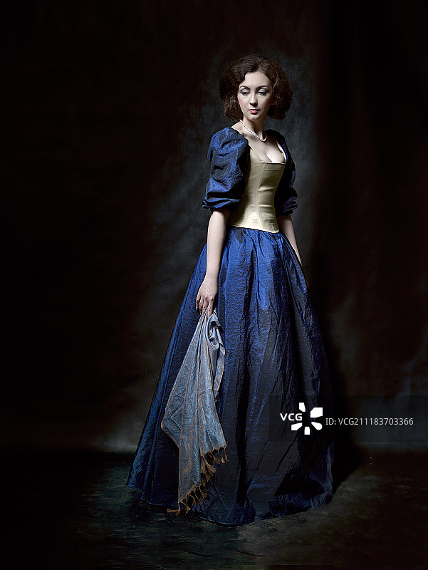 年轻优雅的女子摆姿势拍照在深及脚踝的藏青色连衣裙，拿着丝绸围巾图片素材