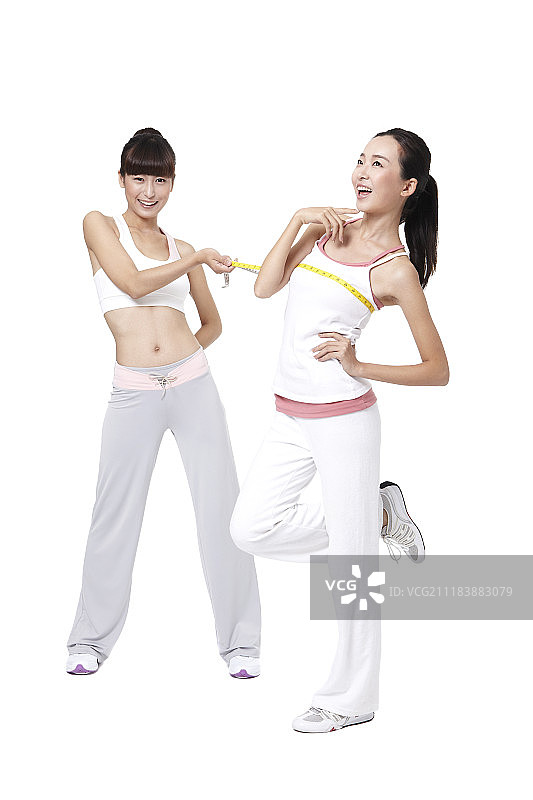 两名妇女用卷尺测量运动服装尺寸的照片图片素材