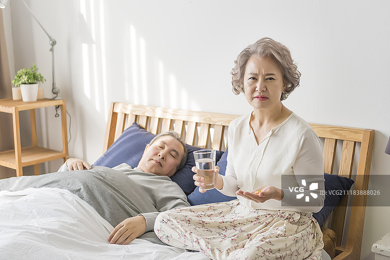 老年妇女为头痛的男人持有药丸的照片图片素材