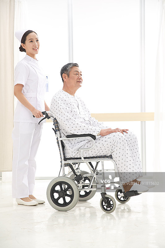 女护士推着坐在轮椅上的老人图片素材