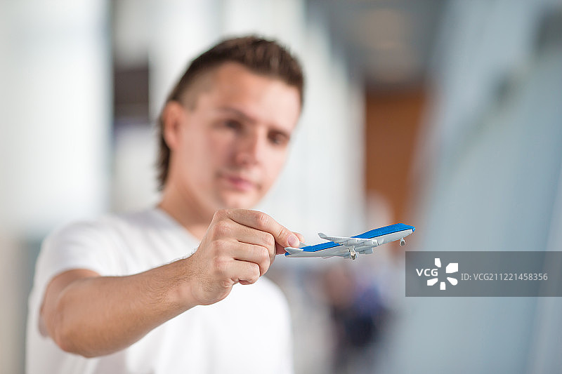 一个年轻人在机场用小飞机等待他的航班图片素材