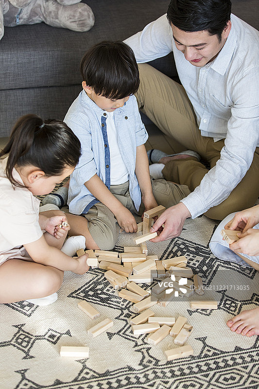 爸爸、妈妈、女儿和儿子一家四口在客厅玩积木图片素材