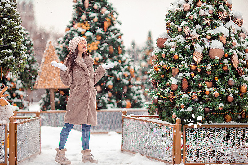 快乐的女孩在雪中的冷杉树枝附近迎接新年图片素材