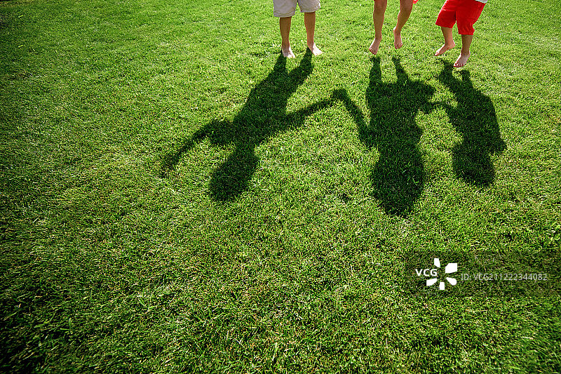 孩子们的影子在草地上三个人的剪影站在他们的手图片素材