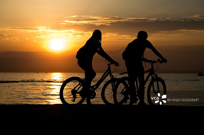 侧视图的夫妇站在海边与他们的自行车和图片素材
