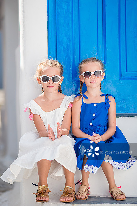 米科诺斯的一个典型的希腊传统村庄里，穿着裙子的小女孩们在街上快乐地走着图片素材