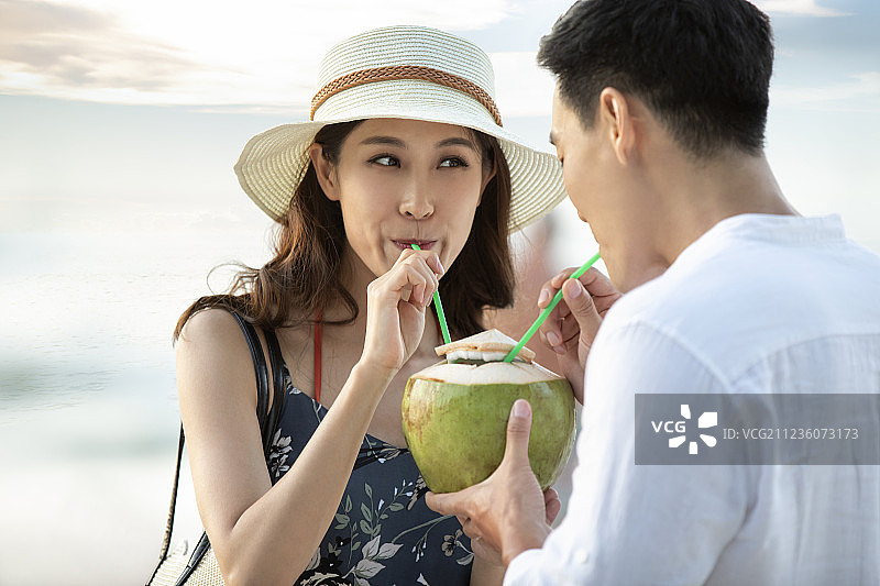 快乐的年轻情侣在沙滩喝椰汁图片素材