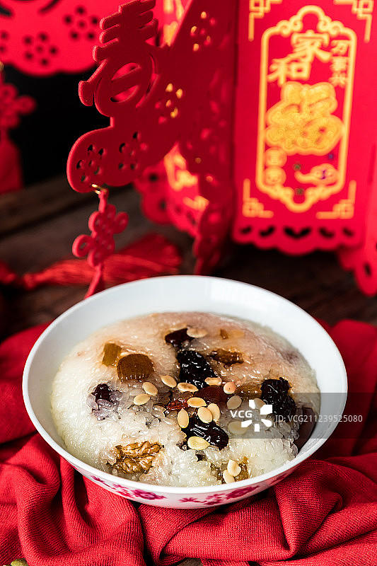 木桌上放着一碗中国传统美食八宝饭和春节装饰品图片素材