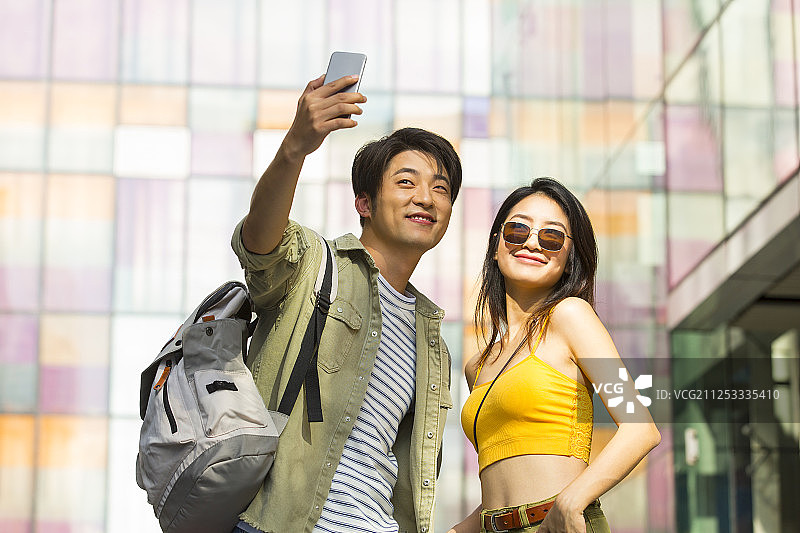浪漫情侣在户外商业街逛街旅游拿手机自拍图片素材