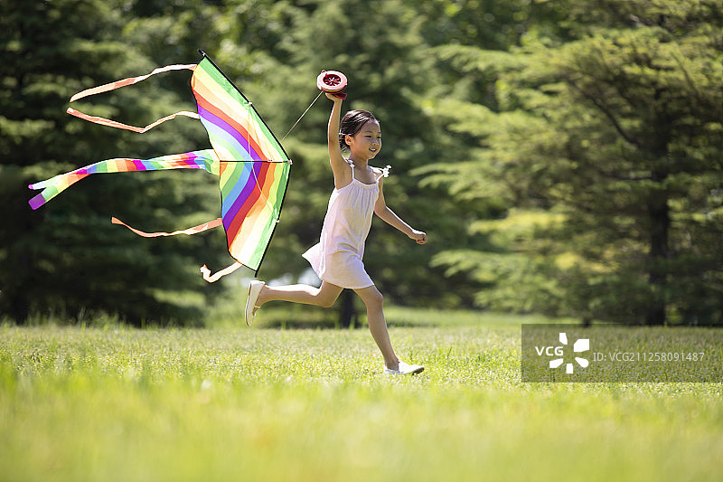快乐的小女孩在草地上放风筝图片素材