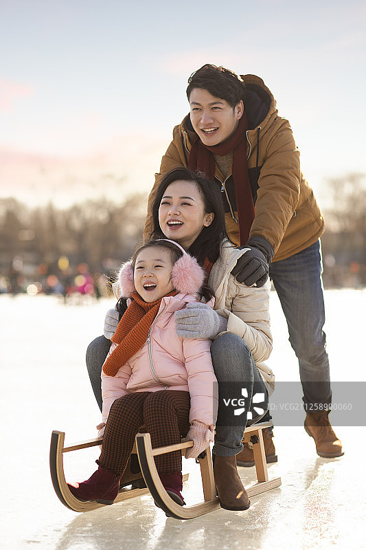 年轻家庭在户外玩雪橇图片素材