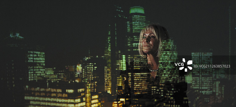 晚上在高楼的灯光下双重曝光的女商人图片素材