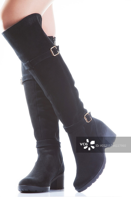 美丽的女性腿在黑色绒面革靴子上的白色背景图片素材