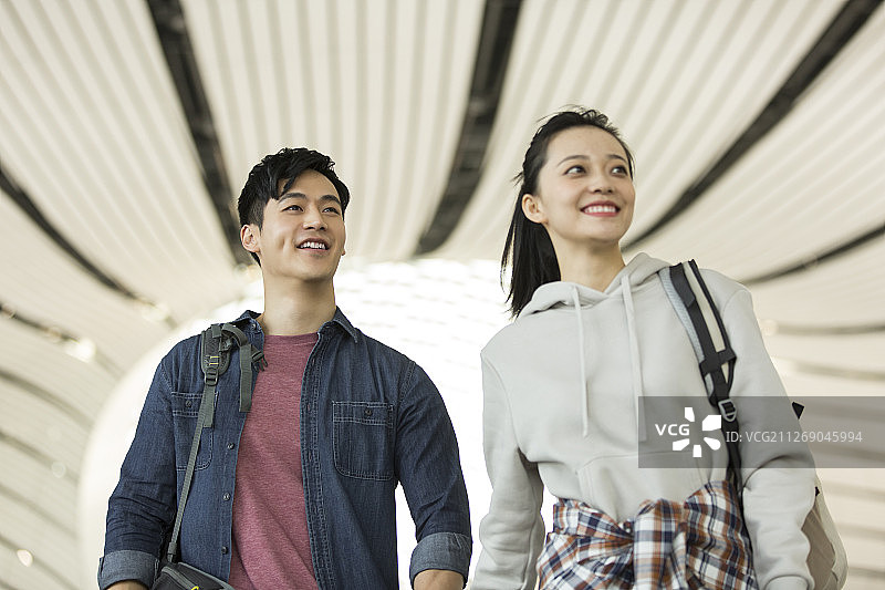 青年情侣背着包手牵手在机场嬉戏交流图片素材