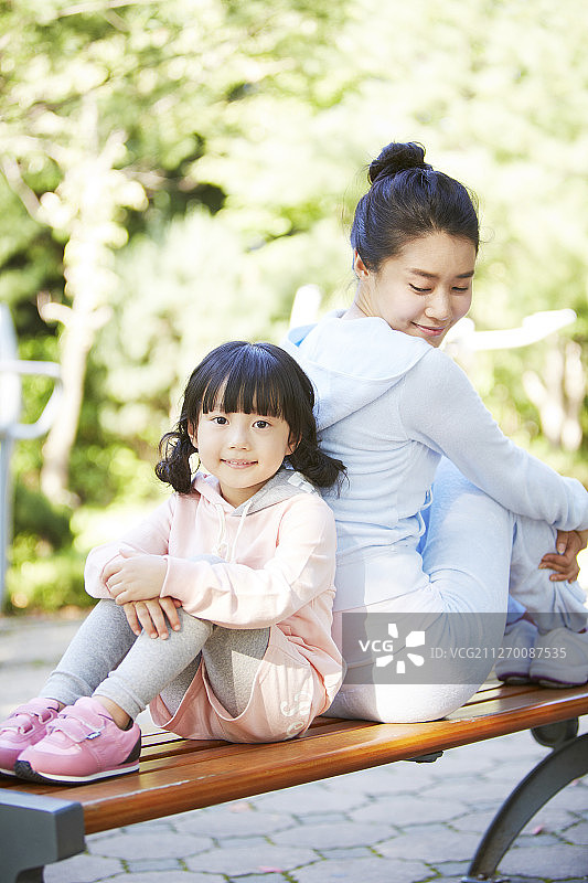 母亲和女儿坐在公园长椅上的照片图片素材