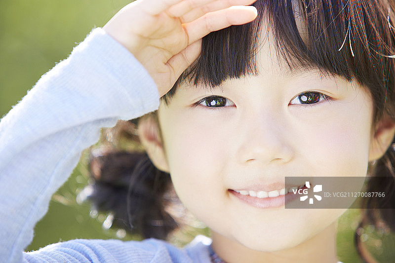 小女孩在公园里用手势微笑的照片图片素材