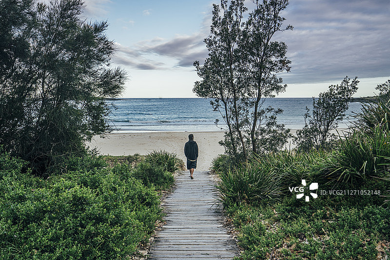 男子走在通往澳大利亚基拉岛田园诗般的海洋海滩的小路上图片素材