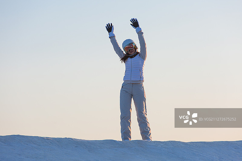 夕阳下青年女子在滑雪场挥手欢呼图片素材