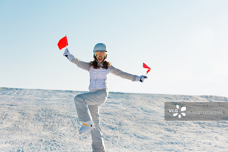一个青年女子在户外滑雪场拿着小红旗为比赛加油喝彩图片素材