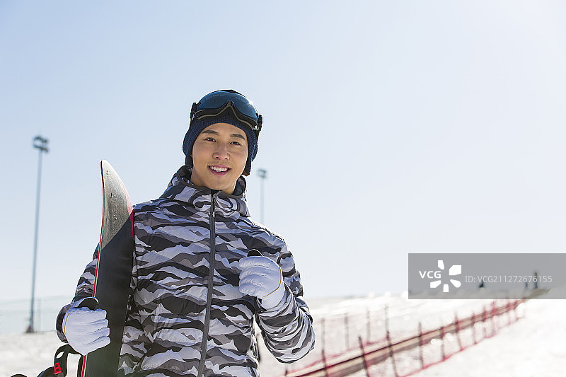 滑雪的青年男子拿着滑雪板肖像图片素材