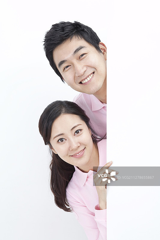 一对穿着粉红色衬衫站在白色空白横幅后面的夫妇的照片图片素材