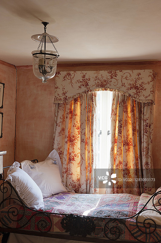窗下装饰华丽的金属床，有浴帘和小圆石图片素材
