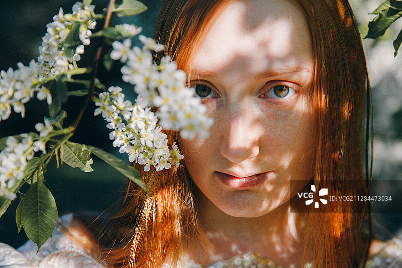 少年长发红发女孩的肖像与白色盛开的植物，莫斯科，俄罗斯图片素材