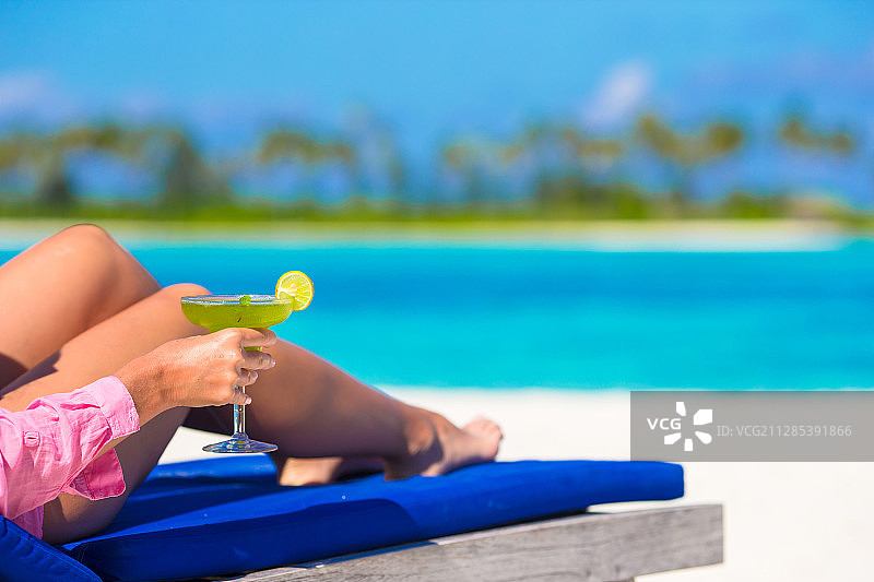 年轻女子与可口的鸡尾酒在白色的热带海滩图片素材
