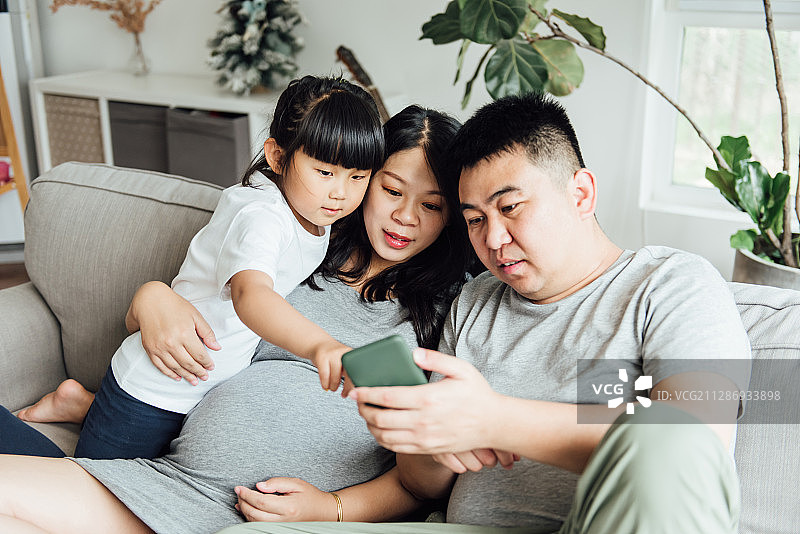 一位亚洲孕妇和丈夫女儿在玩耍图片素材