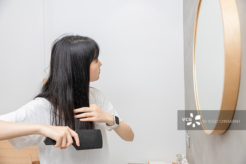 对着镜子，正在梳头的清纯女孩图片素材