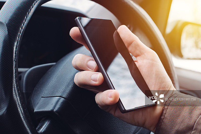 塞尔维亚诺维萨德，一名男子一边开车一边用手机发短信图片素材