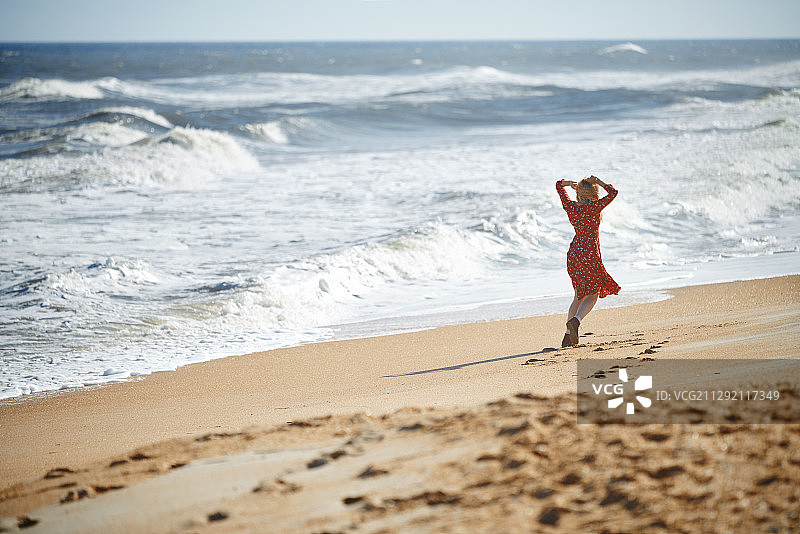 穿着红裙子的快乐女人在海边玩图片素材