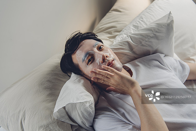 一名男子躺在床上，脸上戴着面具图片素材