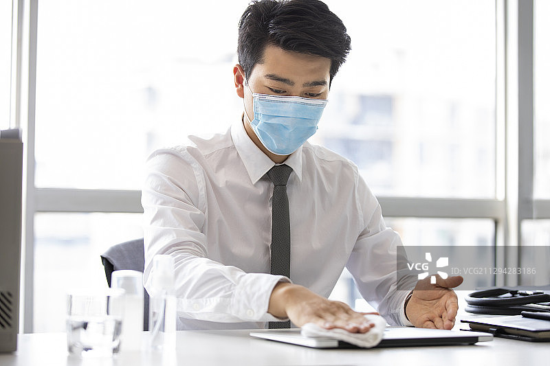年轻的商务男士在办公室使用消毒液杀菌消毒图片素材