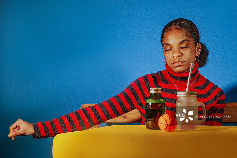 加纳特马，蓝色背景的黑人成年妇女的肖像，用可重复使用的吸管喝可持续的玻璃杯图片素材