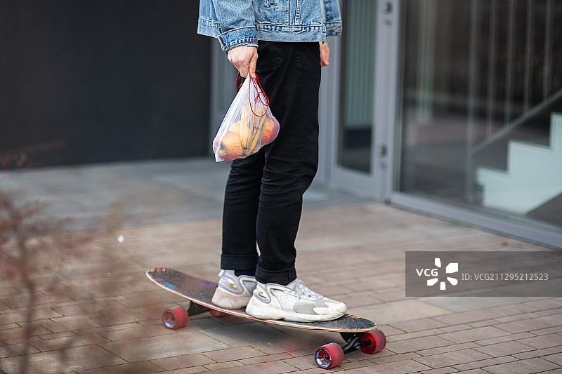 波兰克拉克市，人行道上的矮矮的男人用滑板站在可重复使用的购物袋上图片素材